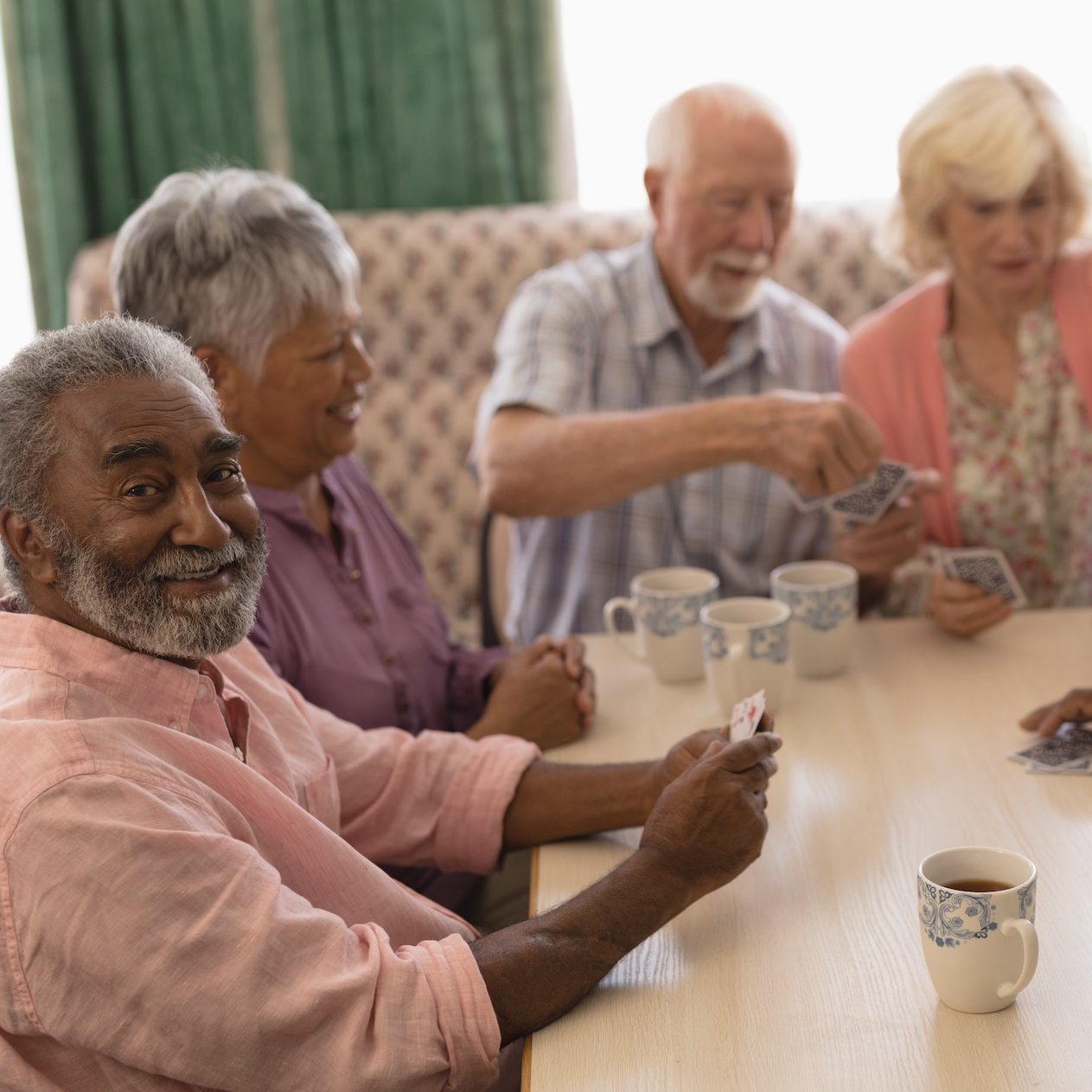 Senior residents playing cards together in a bright and welcoming Oak Crest apartment, enjoying the social lifestyle of independent living in DeKalb, IL.