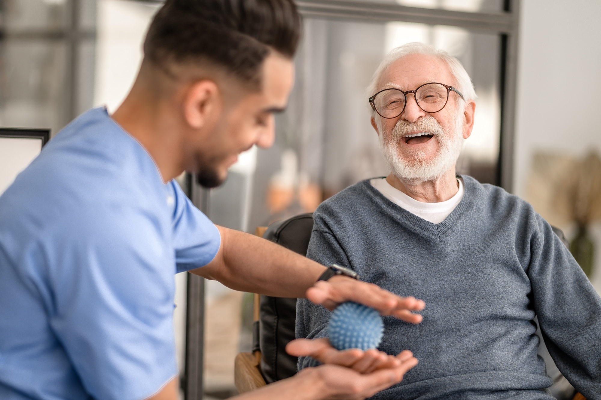Smiling senior man in rehabilitation session with a healthcare professional during short term rehab at Oak Crest.
